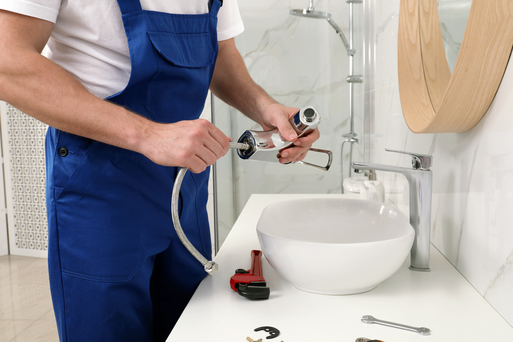 Professional plumber fixing water faucet in bathroom